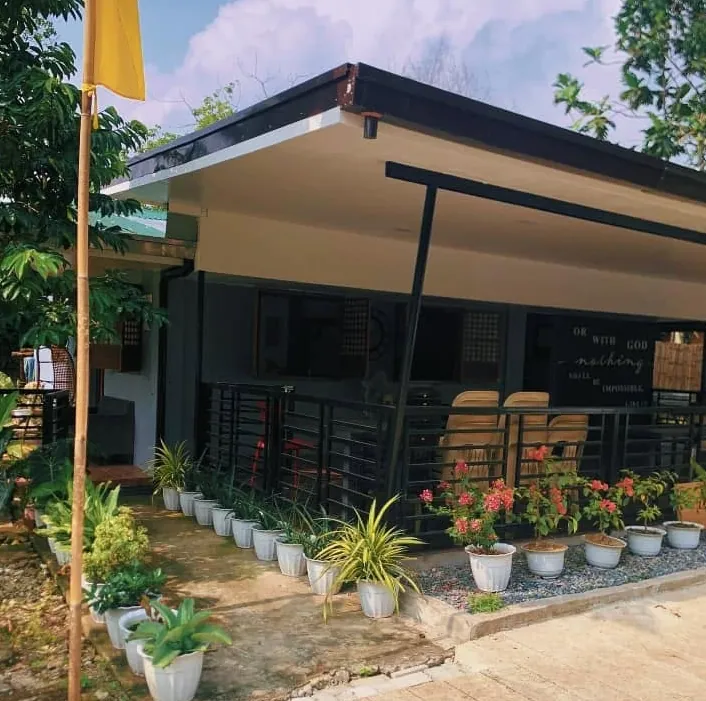 The main house porch lined with potted plants and flowers