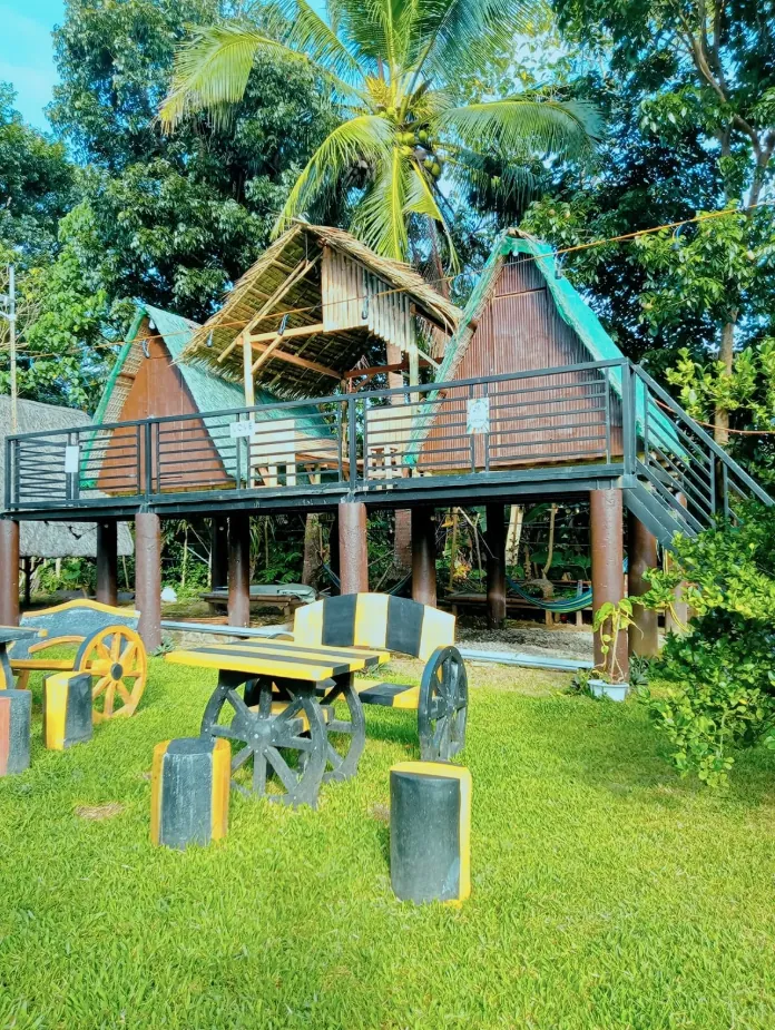Native-style huts on stilts with thatched roofs, surrounded by palms